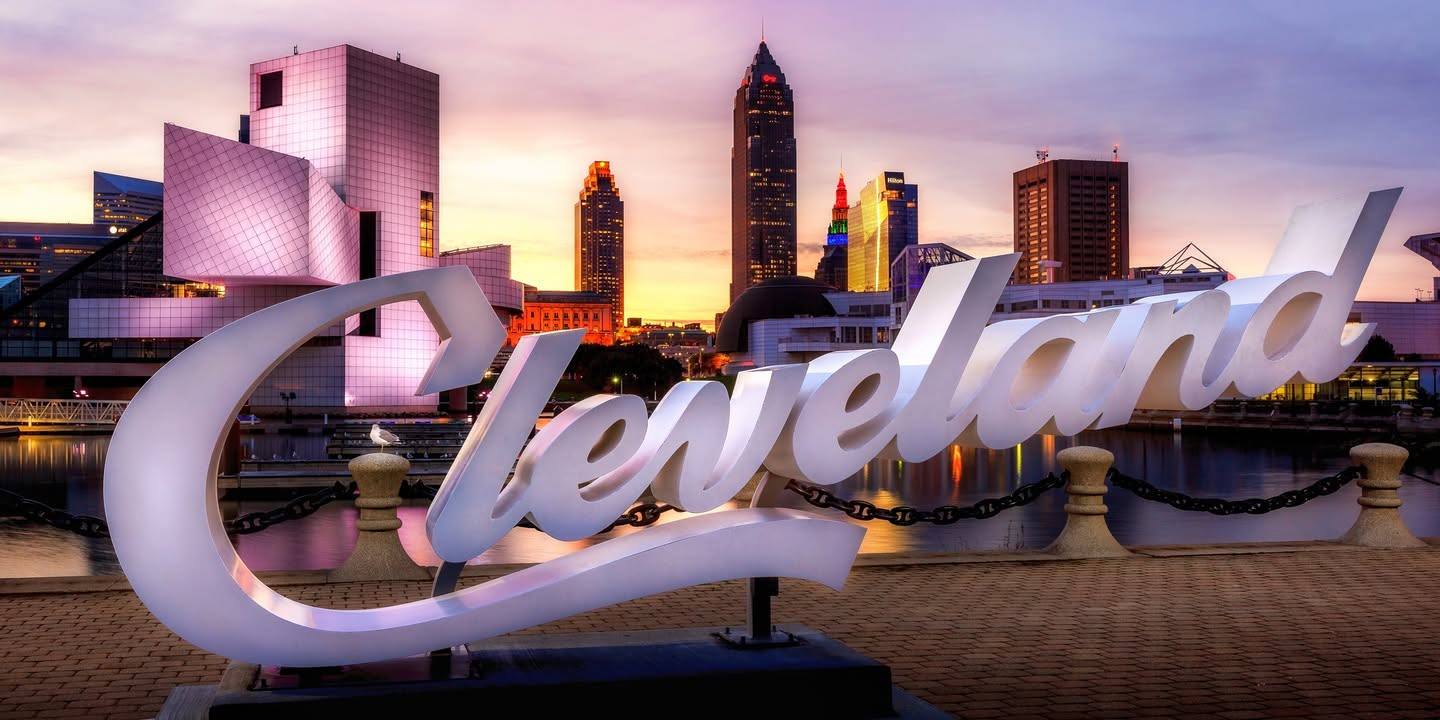 Downtown Cleveland skyline at dusk behind the Cleveland script sign